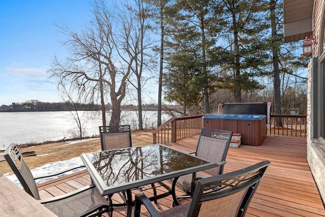 wooden deck featuring outdoor dining space, a hot tub, and a water view