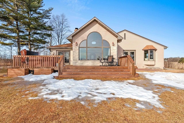 view of front of house featuring stone siding, a chimney, and a deck