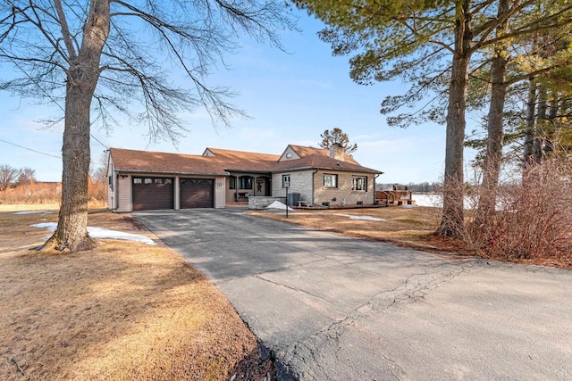 view of front facade with aphalt driveway, an attached garage, and a chimney