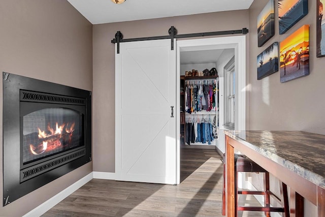 interior space with dark wood finished floors, a barn door, and baseboards