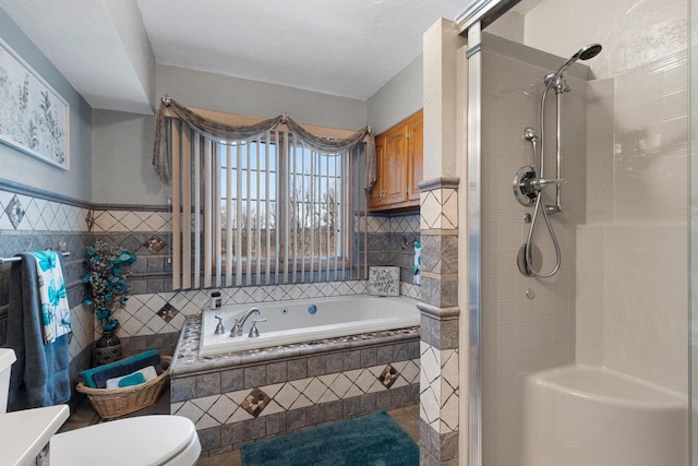 bathroom with a garden tub, toilet, tile walls, and a stall shower