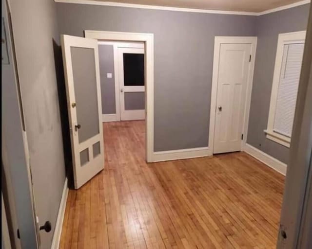 unfurnished room with baseboards, ornamental molding, and light wood finished floors