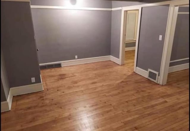 finished below grade area featuring wood finished floors, visible vents, and baseboards