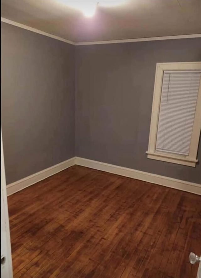 empty room with baseboards, dark wood-style flooring, and crown molding