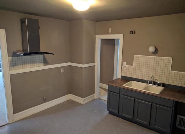 kitchen with decorative backsplash, dark countertops, wall chimney exhaust hood, and a sink