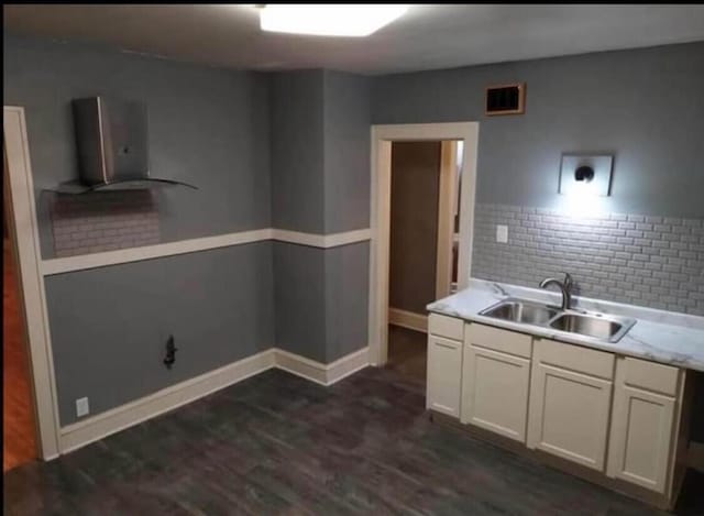 kitchen with visible vents, dark wood-type flooring, a sink, white cabinets, and light countertops