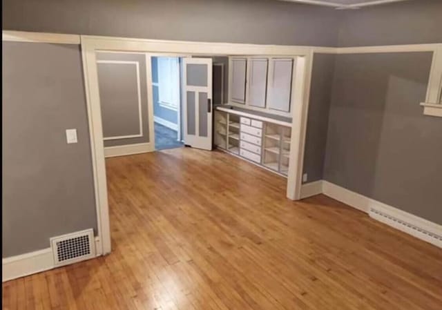 unfurnished bedroom featuring visible vents, baseboards, and wood finished floors