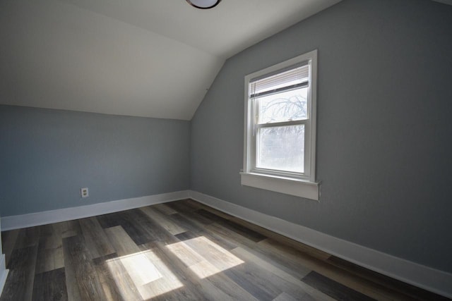 additional living space with vaulted ceiling, baseboards, and dark wood-style flooring