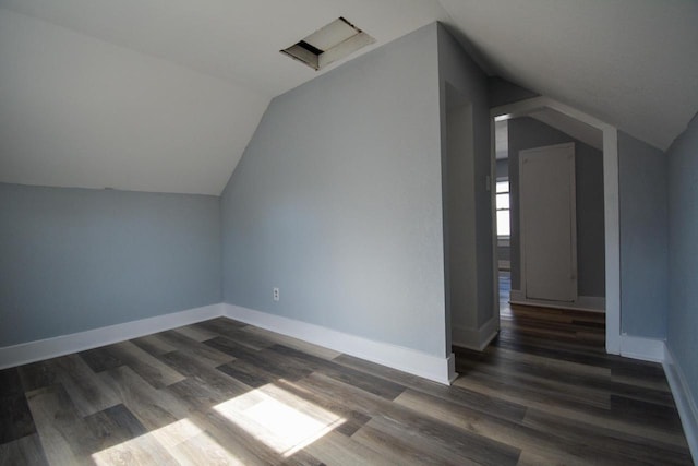 additional living space featuring dark wood finished floors, baseboards, and vaulted ceiling