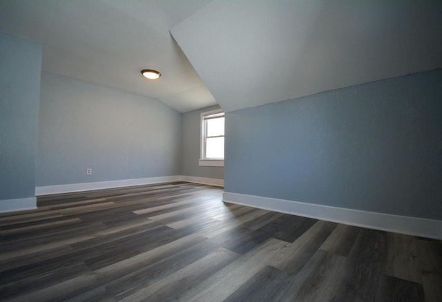 additional living space featuring baseboards, lofted ceiling, and dark wood-style flooring