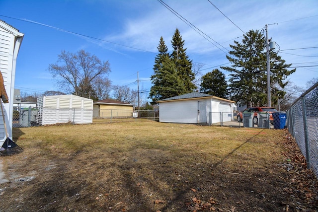 view of yard with a detached garage, an outbuilding, and a fenced backyard