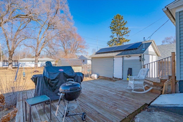 wooden terrace with an outbuilding, a storage unit, fence, and a grill