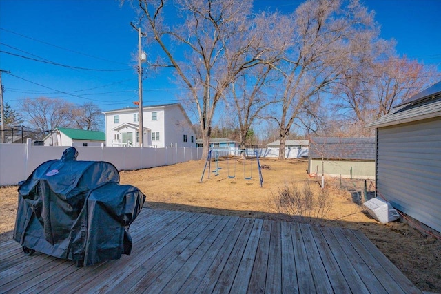 wooden terrace featuring a playground, a yard, and a fenced backyard