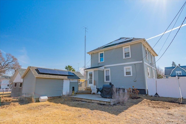 back of house with solar panels, fence, and a wooden deck