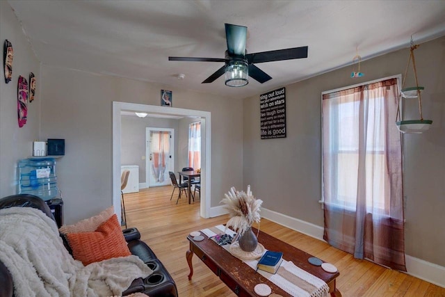 living area featuring ceiling fan, light wood-type flooring, and baseboards