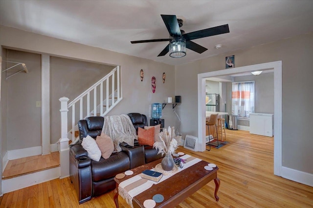 living room with stairway, baseboards, ceiling fan, and wood finished floors