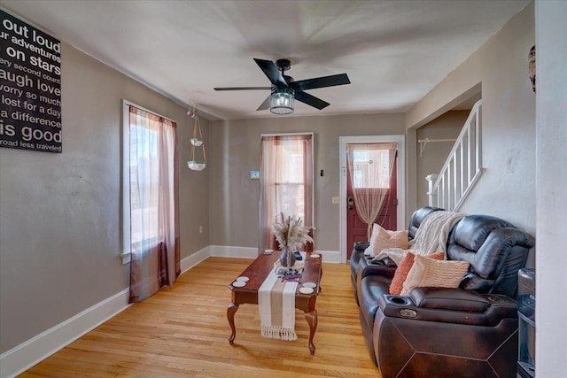 living area with stairway, baseboards, ceiling fan, and wood finished floors