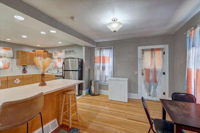 kitchen featuring a breakfast bar, freestanding refrigerator, light wood-style floors, and fridge