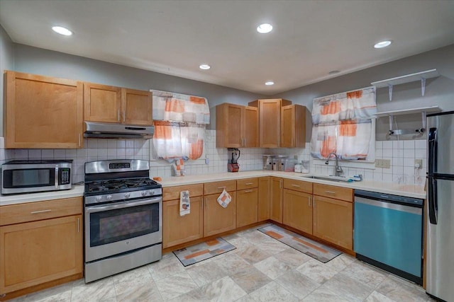 kitchen with under cabinet range hood, light countertops, decorative backsplash, appliances with stainless steel finishes, and a sink