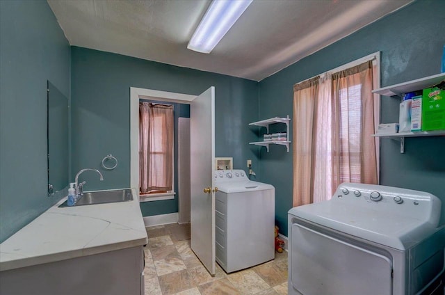 washroom featuring a sink, stone finish flooring, baseboards, laundry area, and separate washer and dryer