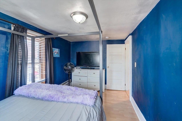 bedroom with light wood finished floors and baseboards