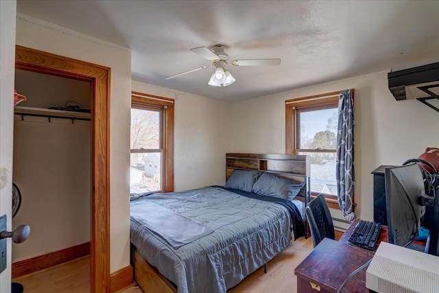 bedroom featuring light wood finished floors, multiple windows, baseboards, and a closet