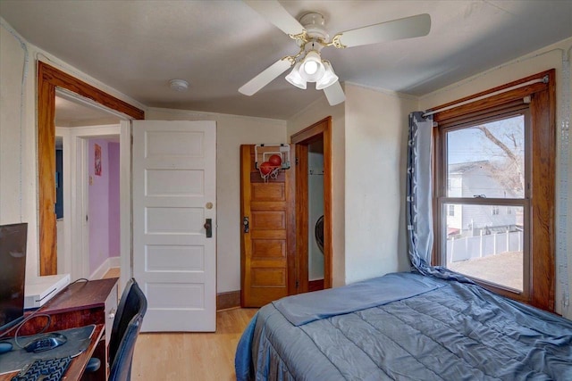 bedroom featuring light wood-style flooring, a ceiling fan, and baseboards