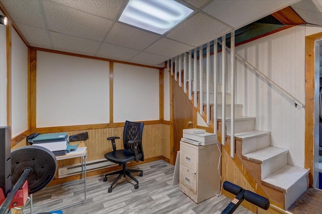 office area featuring a drop ceiling, wood walls, a wainscoted wall, baseboard heating, and wood finished floors