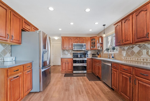 kitchen featuring brown cabinetry, stainless steel appliances, light wood-style floors, and a sink