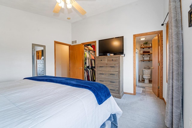 bedroom featuring a spacious closet, visible vents, connected bathroom, light colored carpet, and a closet