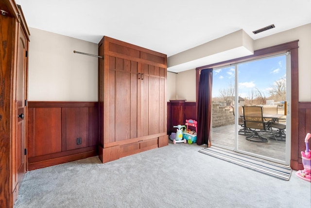 carpeted bedroom with access to exterior, visible vents, and wainscoting