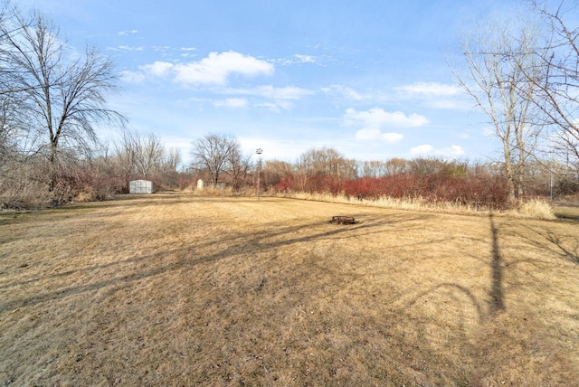 view of yard featuring an outdoor structure, a storage unit, and a rural view