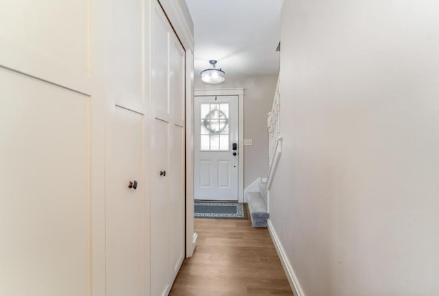 entryway with stairs, baseboards, and light wood finished floors