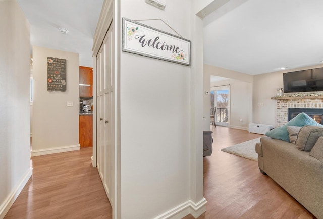 hall with light wood-type flooring and baseboards