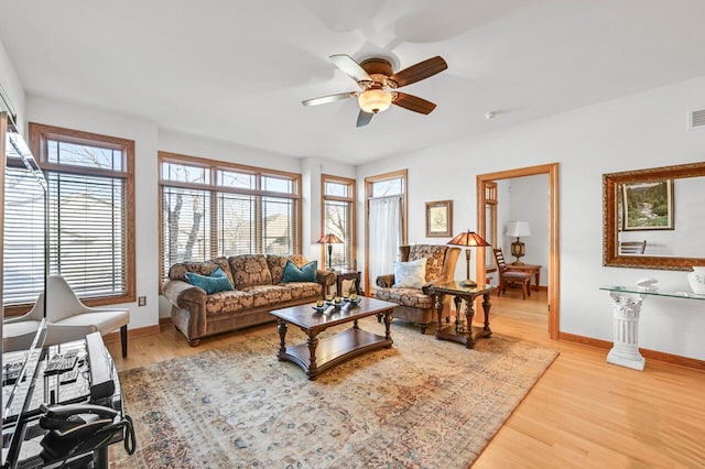 living room with visible vents, baseboards, wood finished floors, and a ceiling fan