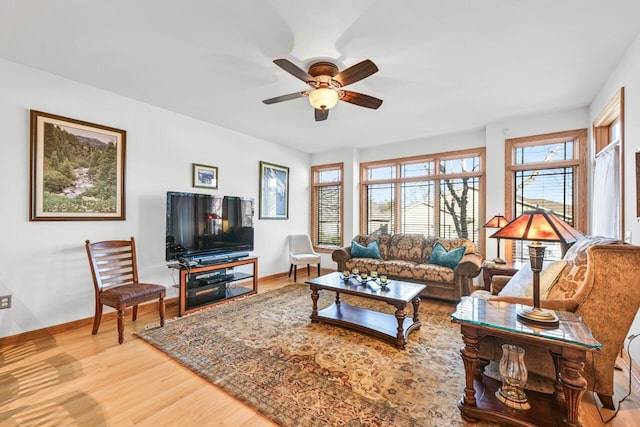 living area with baseboards, wood finished floors, and a ceiling fan