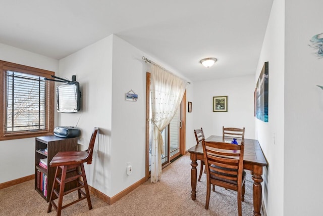 dining room with baseboards and light carpet