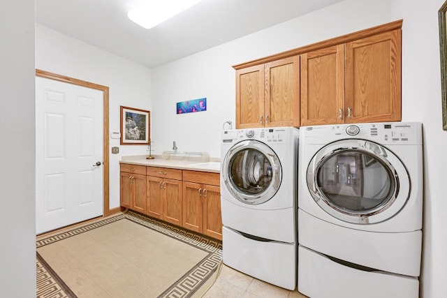 clothes washing area featuring light tile patterned floors, cabinet space, and washing machine and clothes dryer