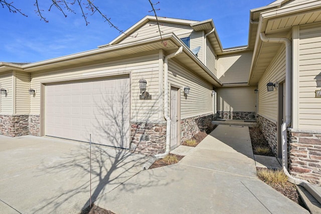 view of side of home with stone siding, driveway, and an attached garage