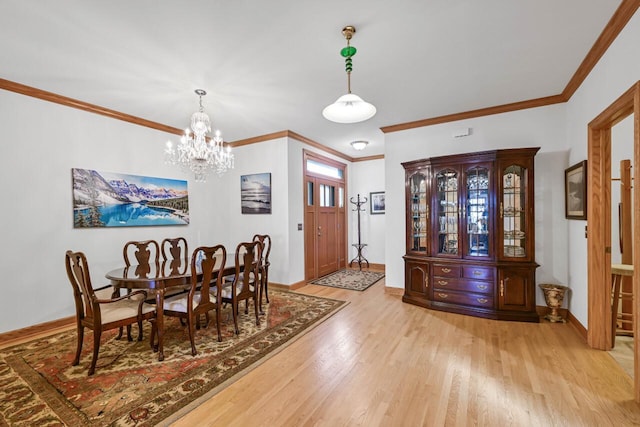 dining room with crown molding, light wood-style flooring, a notable chandelier, and baseboards