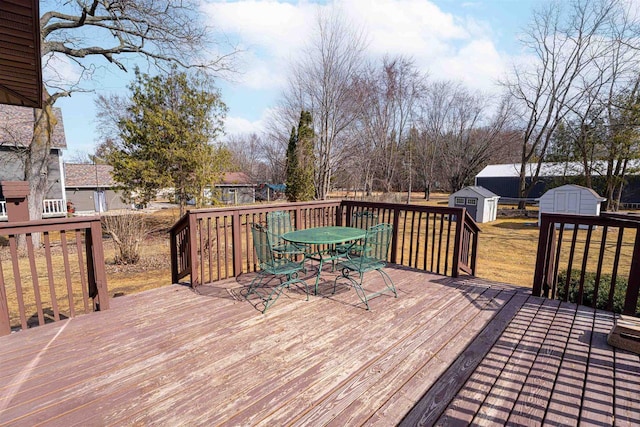 deck featuring an outbuilding, a storage shed, outdoor dining space, and a lawn