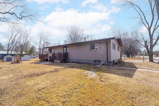 back of house featuring a storage shed, an outbuilding, a lawn, and a wooden deck