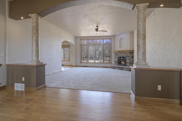 unfurnished living room featuring decorative columns, wood finished floors, visible vents, and ceiling fan