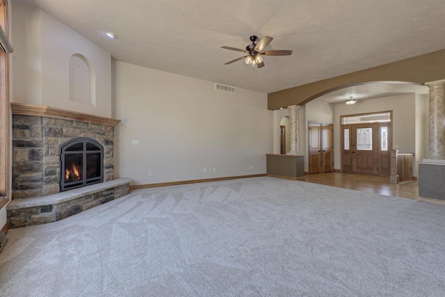 unfurnished living room with decorative columns, arched walkways, visible vents, and ceiling fan