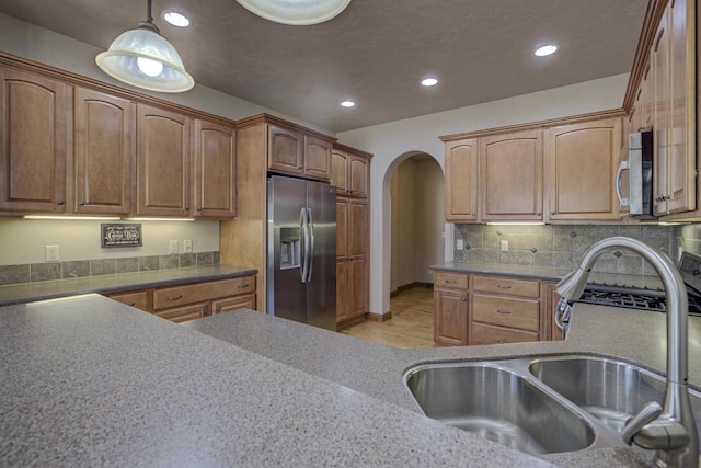 kitchen featuring a sink, tasteful backsplash, recessed lighting, arched walkways, and appliances with stainless steel finishes