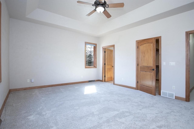 unfurnished bedroom featuring a raised ceiling, baseboards, visible vents, and carpet floors