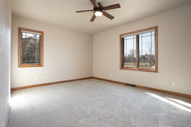 spare room with light carpet, visible vents, baseboards, and ceiling fan