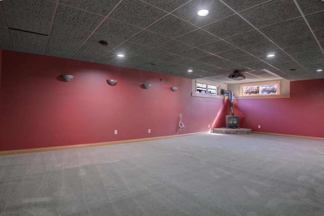 carpeted home theater room with recessed lighting, a paneled ceiling, a wood stove, and baseboards