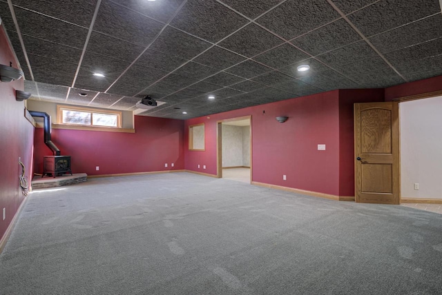 basement featuring recessed lighting, baseboards, carpet, and a wood stove