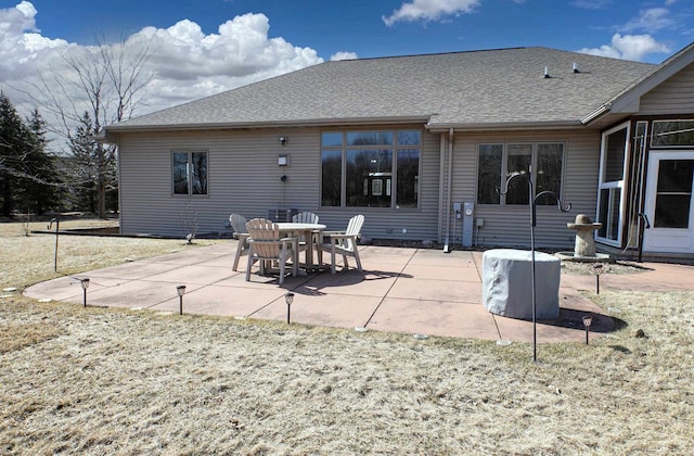 rear view of house featuring a patio and roof with shingles